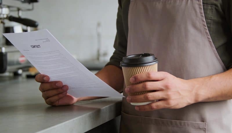 Barista verse du cafe en regardant un contrat
