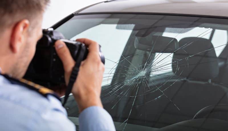 conducteur photographiant pare brise fissure voiture assureur