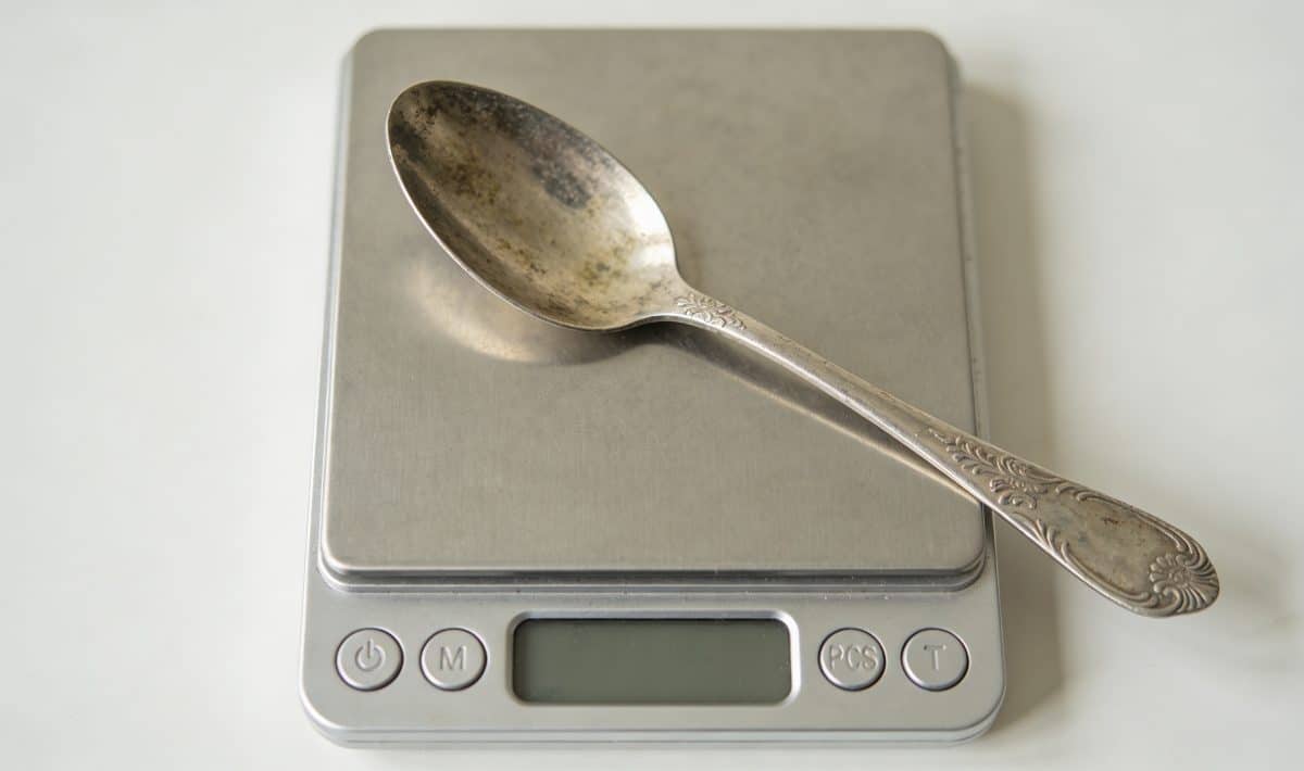 Cuillere en argent patinee posee sur balance numérique