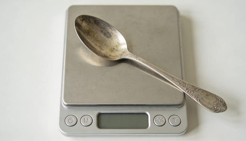Cuillere en argent patinee posee sur balance numérique