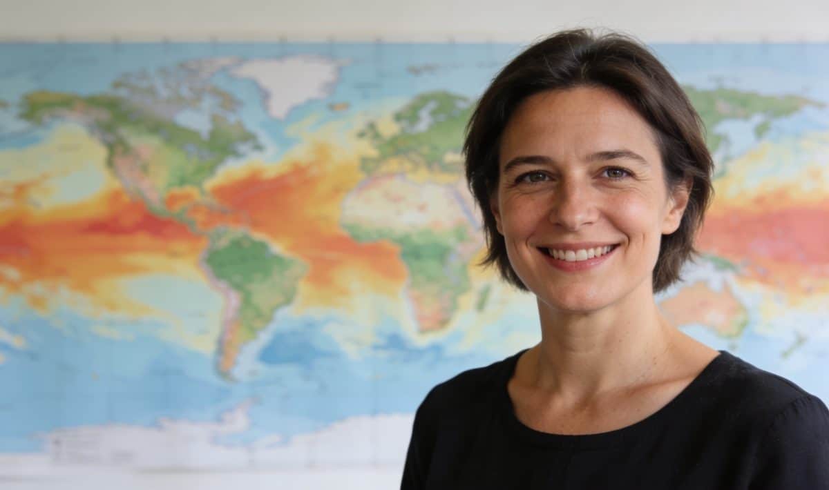 Evelyne Dheliat souriante devant cartes meteo colorées