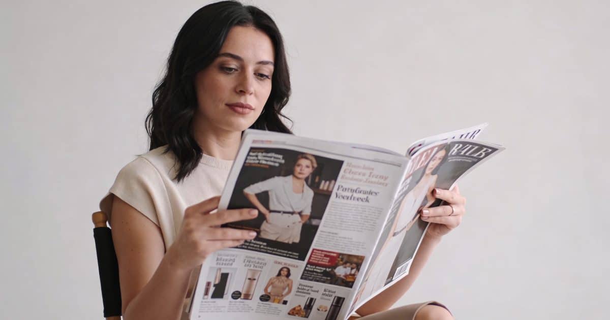 femme assise lisant un magazine rempli de publicites