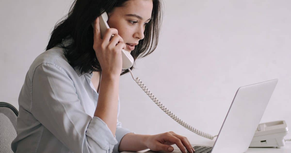 femme assise au telephone devant ordinateur brandt