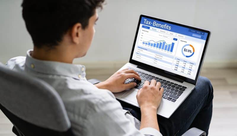 Jeune adulte assis devant ordinateur affichant calcul allocation