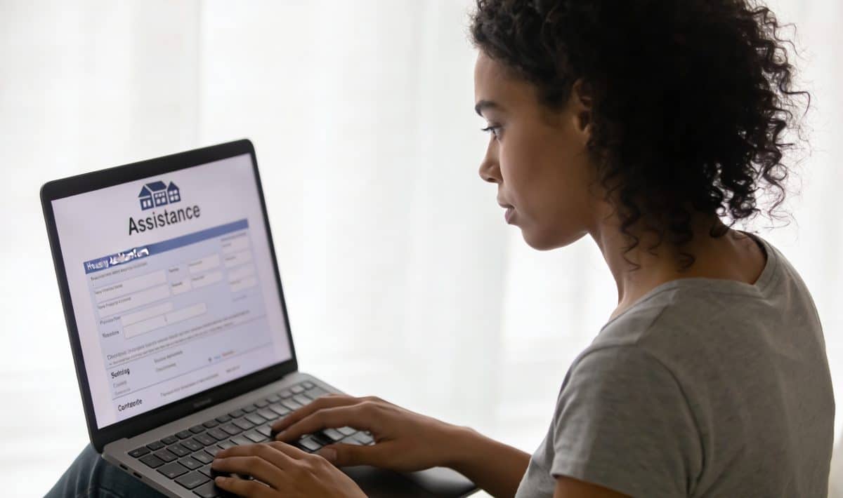 jeune femme assise devant ordinateur consultant formulaire aide logement