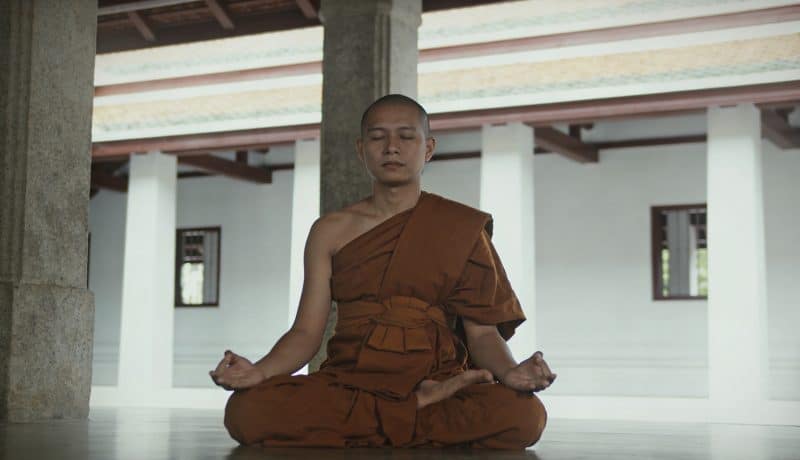 Moine assis en meditation dans temple bouddhiste