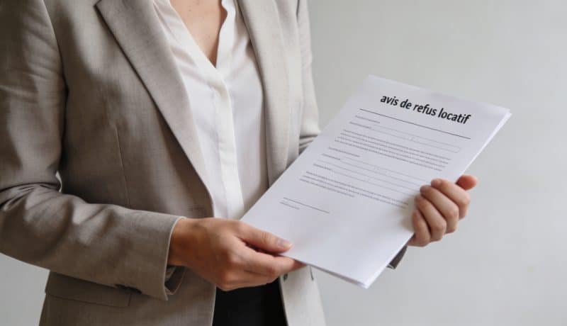 proprietaire debout devant avis de refus locatif