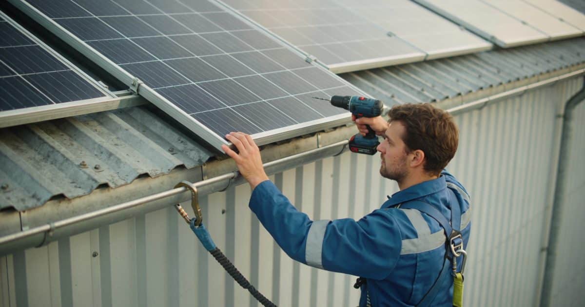 technicien installe panneaux solaires sur toit industriel
